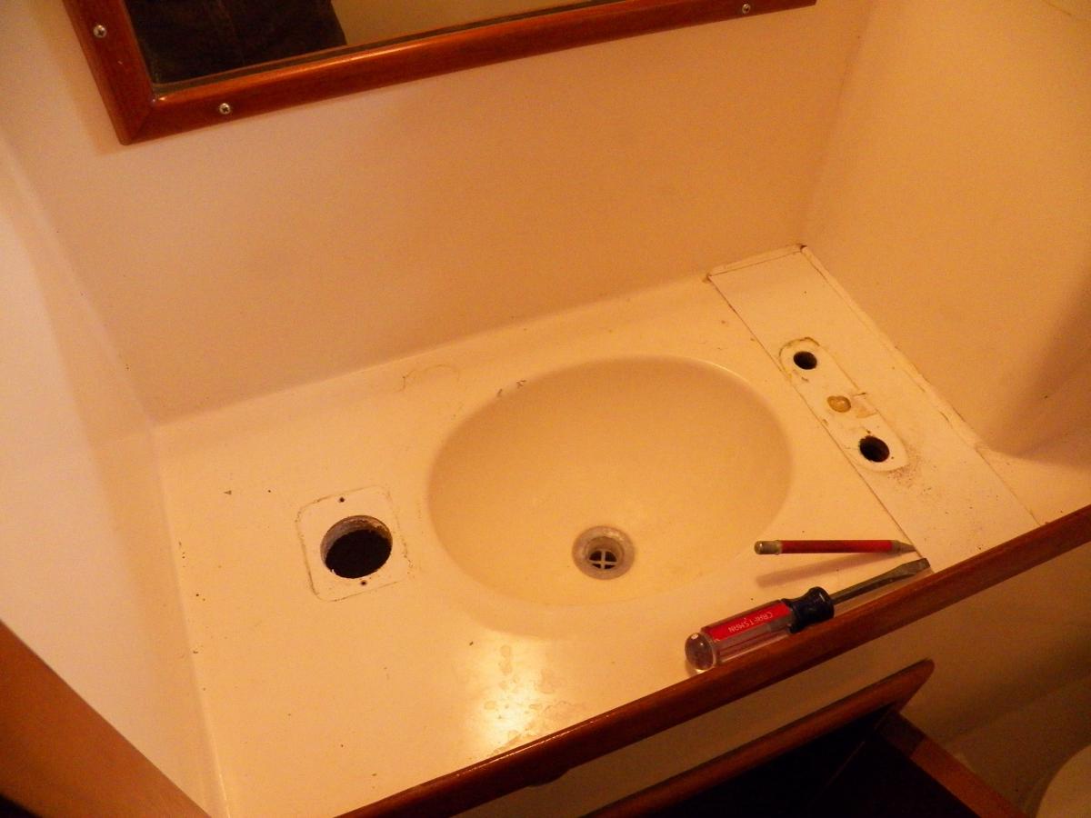 The original little shallow sink. Non-functioning hand pump on the left.  Drain plug lost.  Faucet on the right.